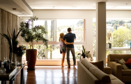A couple standing and looking through a large window.