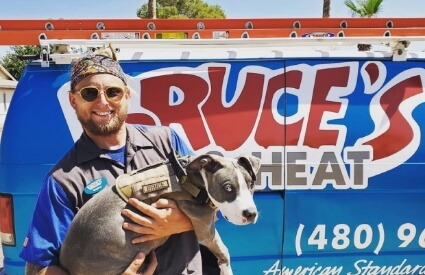 A Bruce's AC & Heating technician holding a dog.