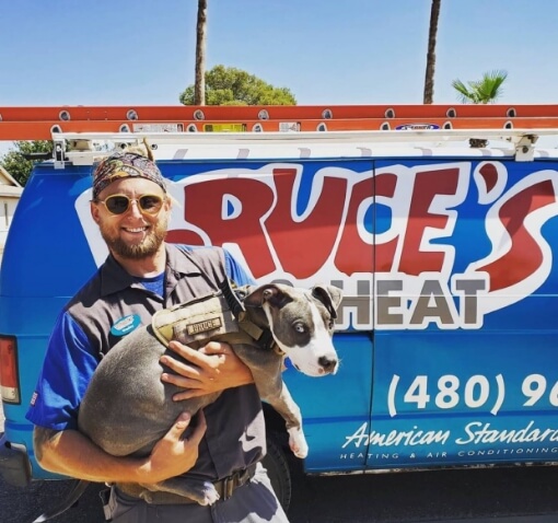 Holding a dog in front of a Bruce's AC & Heating service truck.